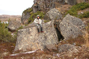 Jordanna Benuen beside an old meat cache on the island in the narrows at the northeast corner of Kameshtashtan. It probably dates to about 1900 based on the rotten wood found in front. You can see where boulders have been piled on top to cover the crack in the rocks. Photo courtesy Stephen Loring.