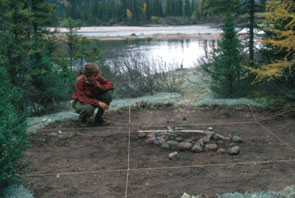 Eric Loring at a late 19th, early 20th century Innu tent ring with a central stone fireplace at an old Innu camp on the west shore of Kameshtashtan-shipu, just upstream from the junction with Ashuapun-shipu and Emish-shipu. Photo courtesy Stephen Loring.